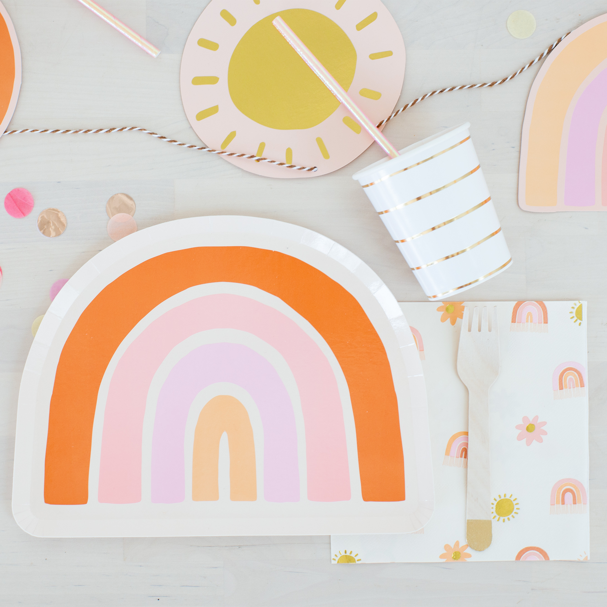 Colorful rainbow-themed plates, cups, and napkins on a light gray background