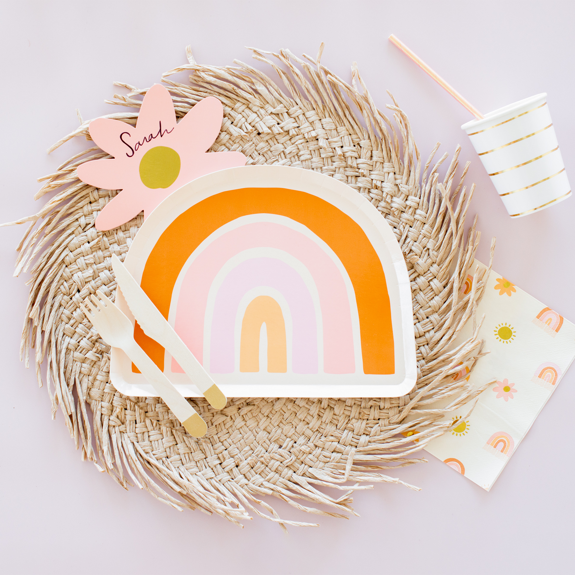 Colorful rainbow-shaped plate with a straw placemat on a light background